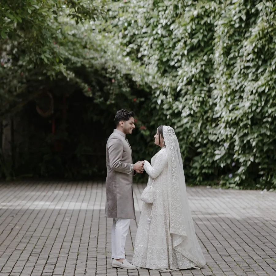 Murshida and Ashique holding hands in a leafy courtyard